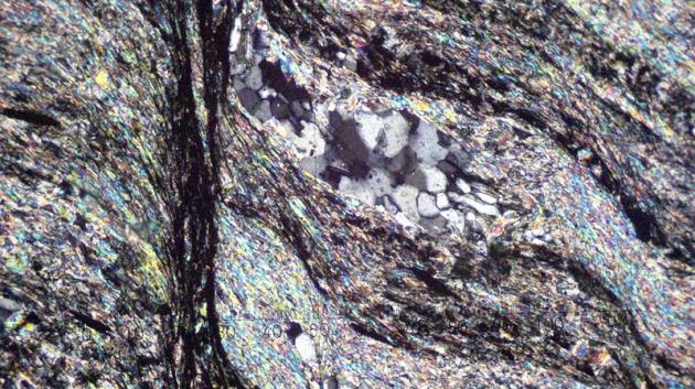 Metamorfovaná hornina fylit pod mikroskopem, zvětšeno 100x. (foto: Chmee2, 2003, CC BY-SA 3.0)
